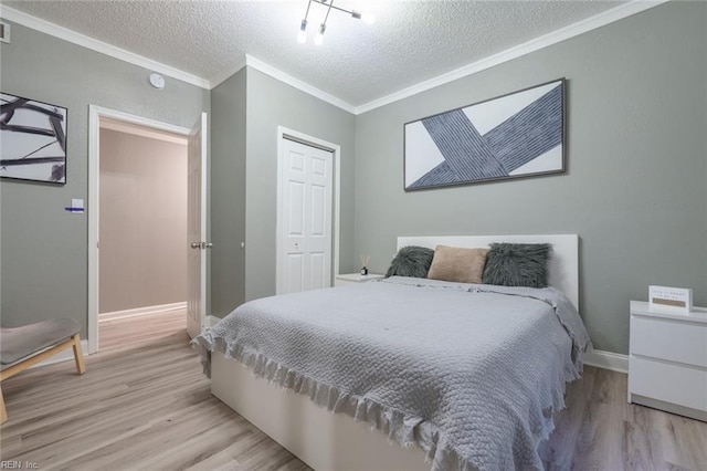 bedroom featuring crown molding, light hardwood / wood-style floors, a closet, and a textured ceiling