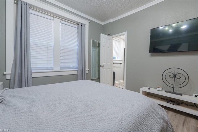 bedroom featuring ornamental molding, connected bathroom, hardwood / wood-style floors, and a textured ceiling