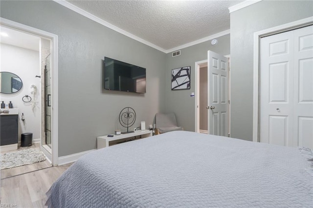 bedroom featuring ornamental molding, a textured ceiling, light wood-type flooring, and a closet