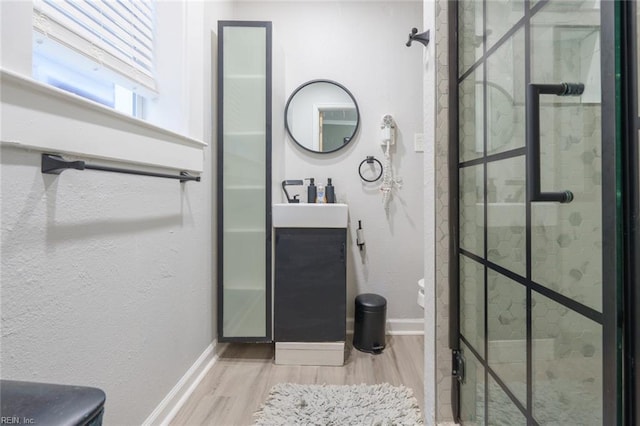 bathroom featuring a tile shower, vanity, and wood-type flooring