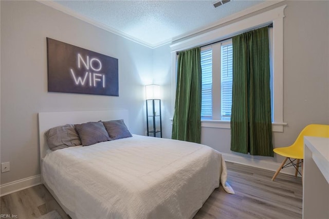 bedroom with hardwood / wood-style flooring, crown molding, and a textured ceiling