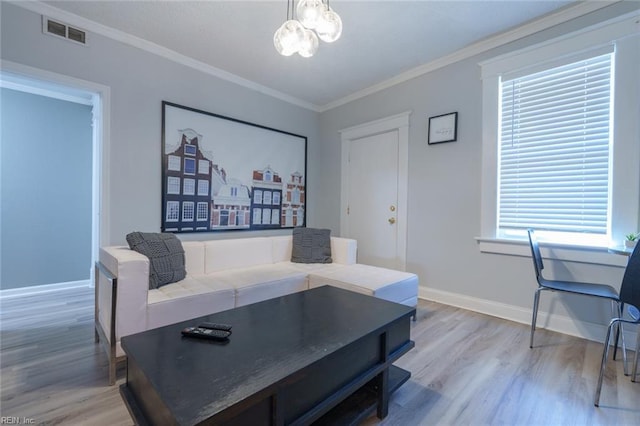 living room with crown molding, a notable chandelier, a wealth of natural light, and light wood-type flooring