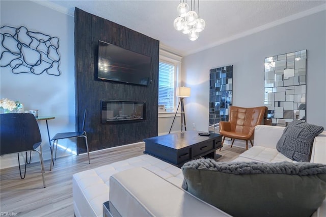 living room with a large fireplace, ornamental molding, light hardwood / wood-style floors, and a notable chandelier