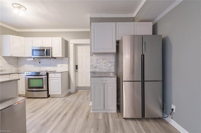 kitchen featuring tasteful backsplash, white cabinetry, appliances with stainless steel finishes, and ornamental molding