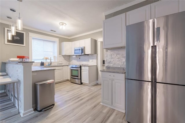 kitchen featuring appliances with stainless steel finishes, white cabinetry, a kitchen breakfast bar, tasteful backsplash, and light hardwood / wood-style floors