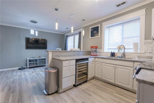 kitchen featuring sink, white cabinetry, light hardwood / wood-style flooring, kitchen peninsula, and beverage cooler