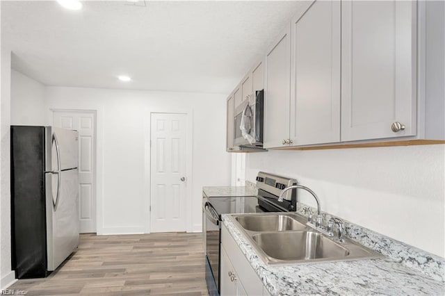 kitchen with white cabinetry, appliances with stainless steel finishes, sink, and light hardwood / wood-style floors