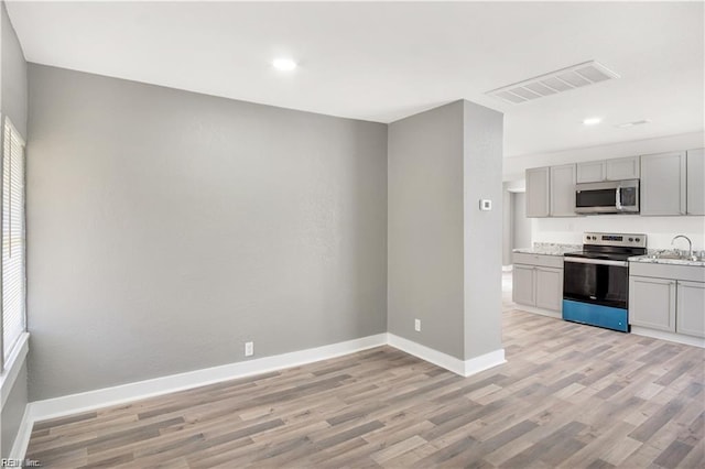 kitchen featuring appliances with stainless steel finishes, sink, gray cabinetry, and light hardwood / wood-style floors