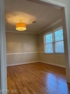 spare room featuring hardwood / wood-style flooring and ornamental molding