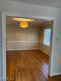 unfurnished dining area featuring crown molding and dark wood-type flooring