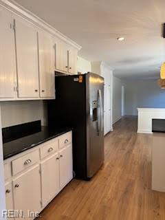 kitchen with stainless steel fridge, white cabinets, and light wood-type flooring