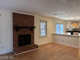 unfurnished living room with a brick fireplace and wood-type flooring