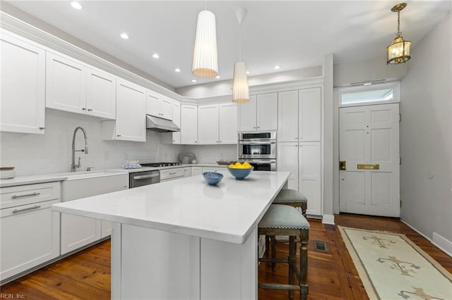 kitchen featuring white cabinetry, hanging light fixtures, a kitchen breakfast bar, and appliances with stainless steel finishes