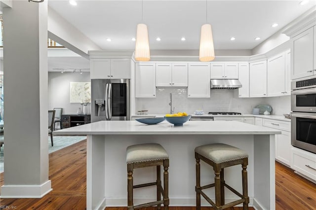 kitchen with a breakfast bar, decorative light fixtures, a center island, stainless steel appliances, and white cabinets