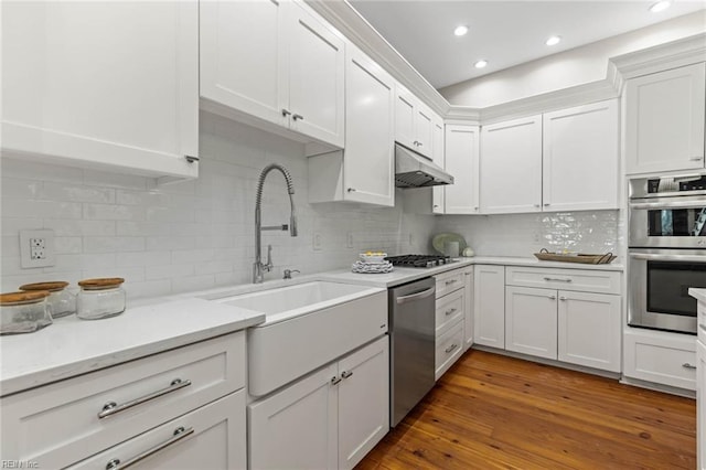 kitchen with sink, stainless steel appliances, white cabinets, dark hardwood / wood-style flooring, and decorative backsplash