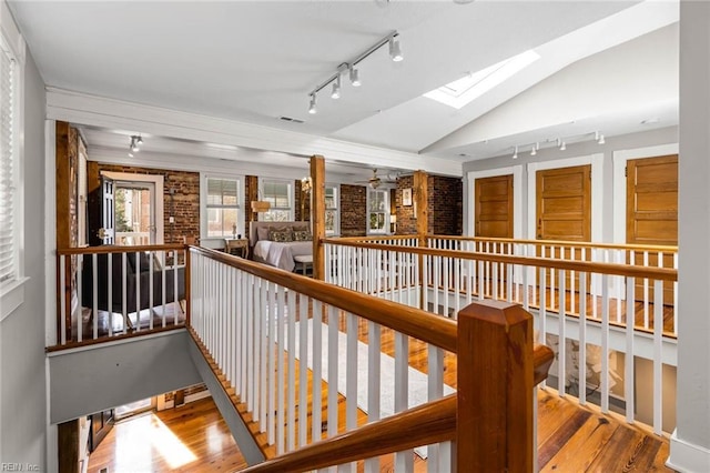 hall featuring vaulted ceiling with skylight, track lighting, and light wood-type flooring