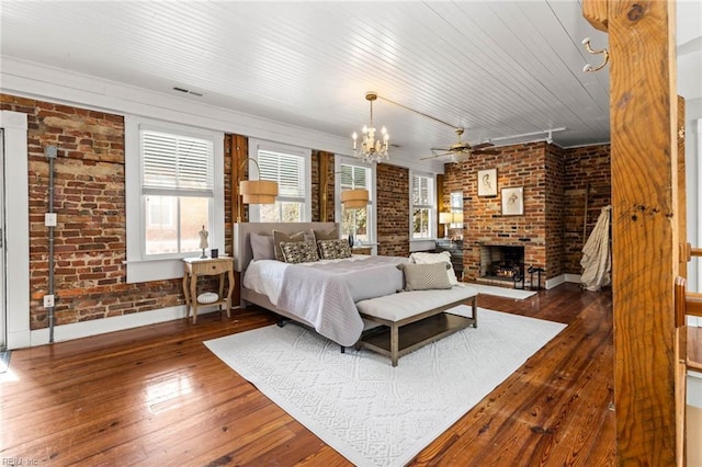 bedroom featuring brick wall, dark hardwood / wood-style flooring, a brick fireplace, wooden ceiling, and a chandelier