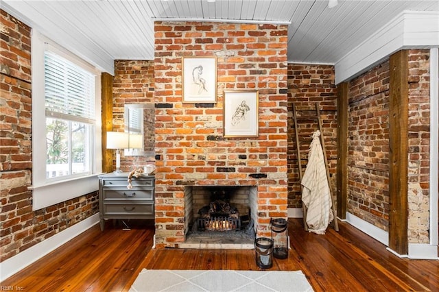 living room featuring brick wall, dark hardwood / wood-style flooring, and a brick fireplace