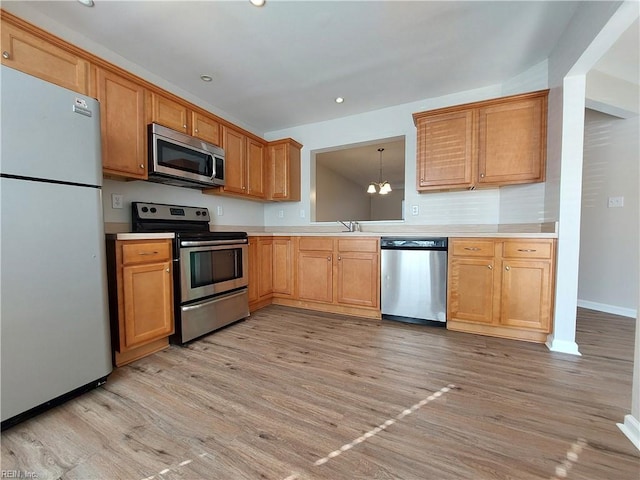 kitchen featuring sink, decorative light fixtures, light hardwood / wood-style flooring, appliances with stainless steel finishes, and a notable chandelier