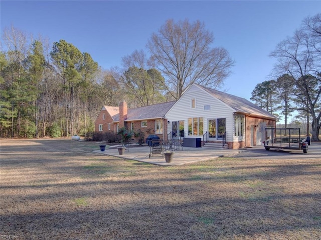 view of front facade with central AC, a patio area, and a front yard