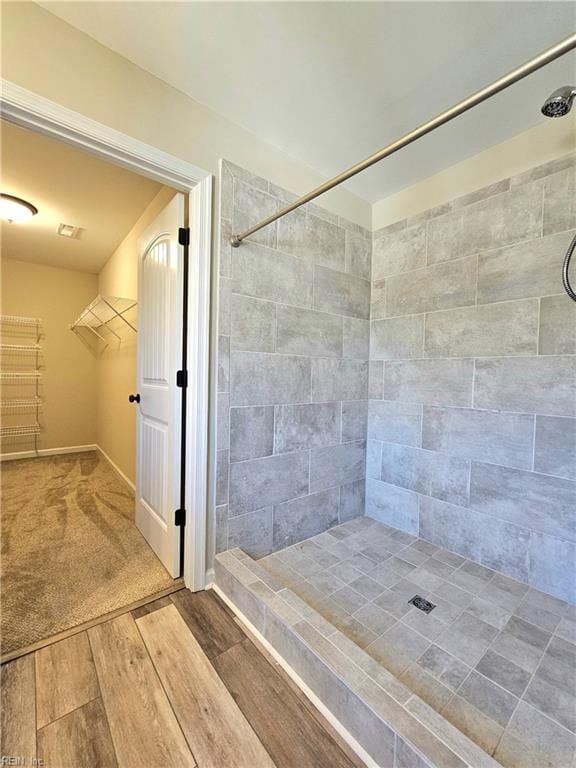 bathroom with wood-type flooring and a tile shower