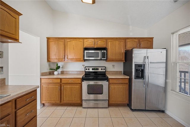 kitchen with lofted ceiling, light tile patterned floors, and stainless steel appliances