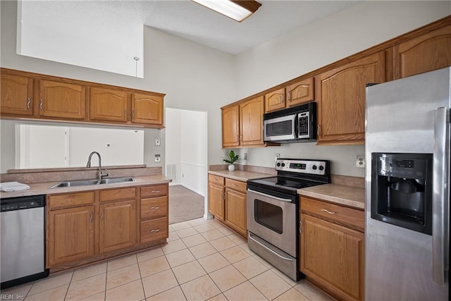 kitchen with a towering ceiling, appliances with stainless steel finishes, sink, and light tile patterned floors