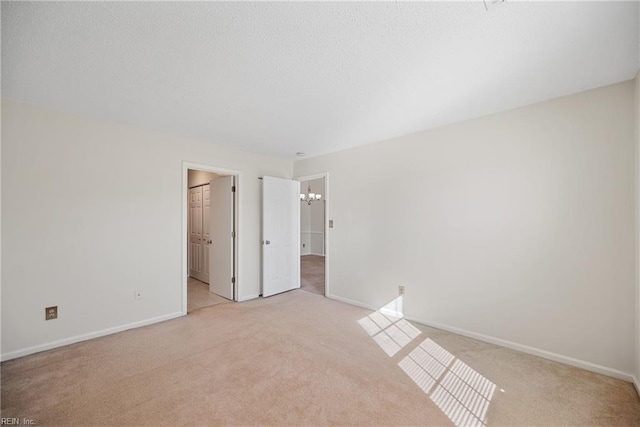 carpeted spare room featuring a chandelier