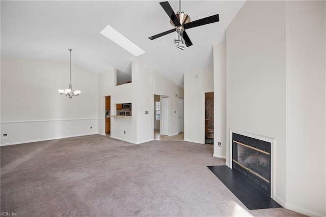 unfurnished living room with carpet floors, ceiling fan with notable chandelier, high vaulted ceiling, and a skylight