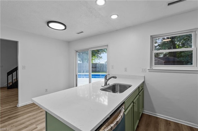 kitchen with dishwasher, sink, green cabinets, light hardwood / wood-style floors, and kitchen peninsula