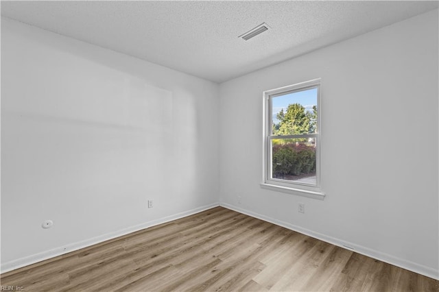 empty room featuring a textured ceiling and light hardwood / wood-style floors