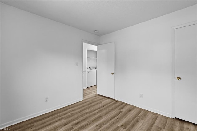 unfurnished bedroom with washing machine and clothes dryer and light hardwood / wood-style floors