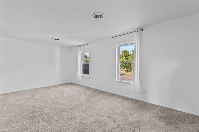 carpeted empty room with a textured ceiling