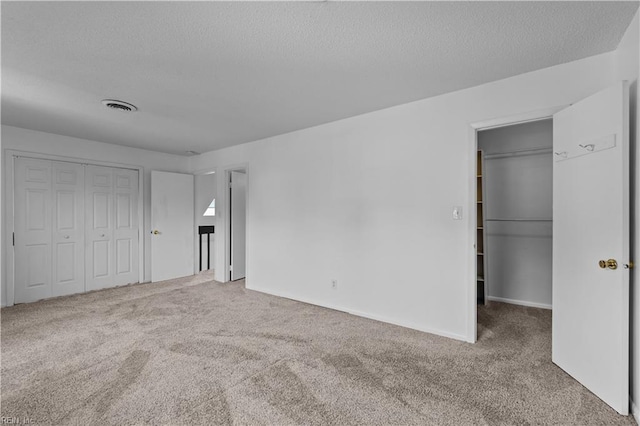 unfurnished bedroom featuring carpet flooring, a textured ceiling, and a closet