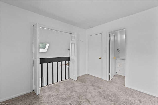 interior space featuring ensuite bathroom, a skylight, and light carpet