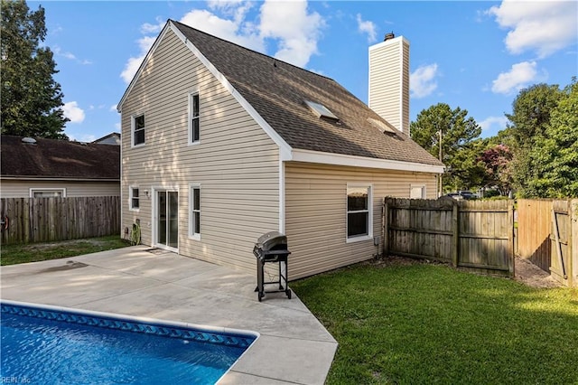 rear view of house with a yard, a fenced in pool, and a patio area