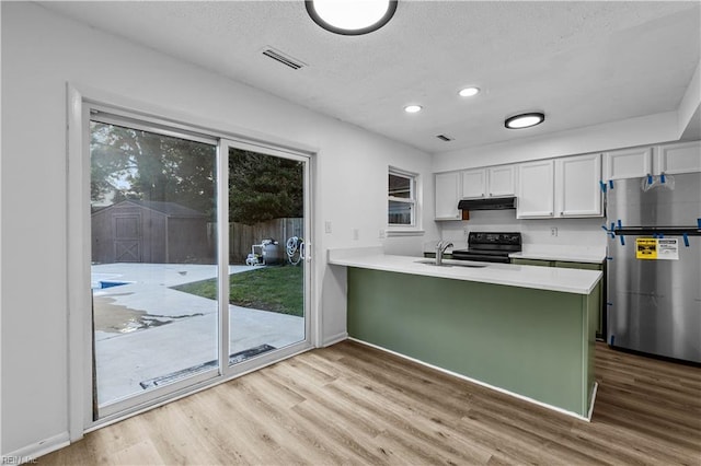 kitchen with white cabinets, sink, stainless steel fridge, and kitchen peninsula