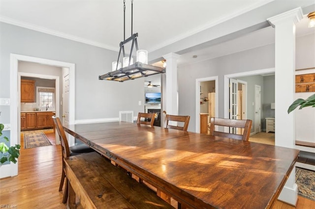 dining space featuring sink, decorative columns, crown molding, ceiling fan, and light hardwood / wood-style floors