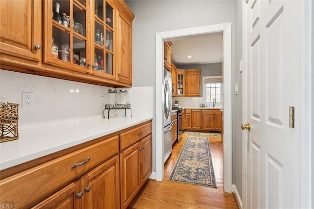 kitchen featuring sink, backsplash, light hardwood / wood-style flooring, and appliances with stainless steel finishes