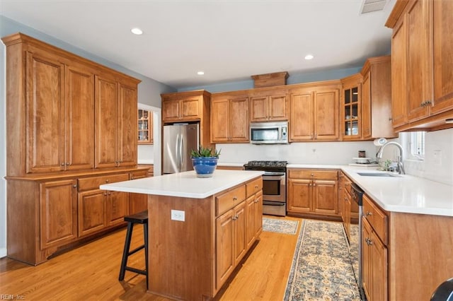 kitchen with a kitchen island, sink, a kitchen breakfast bar, light hardwood / wood-style floors, and stainless steel appliances