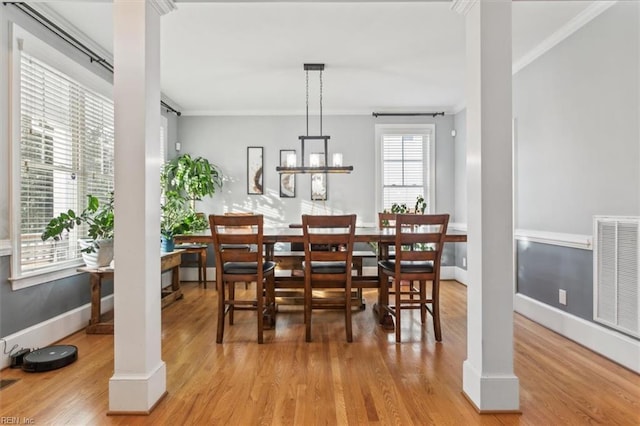 dining space with an inviting chandelier, ornamental molding, light hardwood / wood-style flooring, and ornate columns