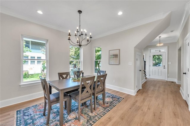 dining space featuring crown molding, an inviting chandelier, and light hardwood / wood-style flooring