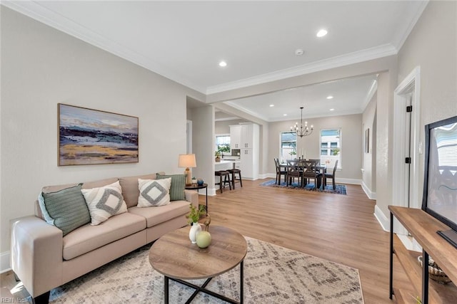 living room featuring crown molding, light hardwood / wood-style flooring, and a notable chandelier