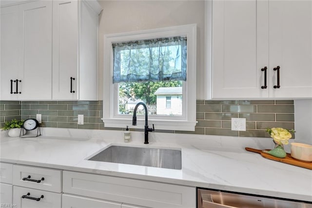 kitchen featuring sink, stainless steel dishwasher, white cabinets, light stone countertops, and backsplash