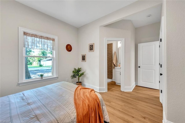 bedroom featuring multiple windows, connected bathroom, and light wood-type flooring