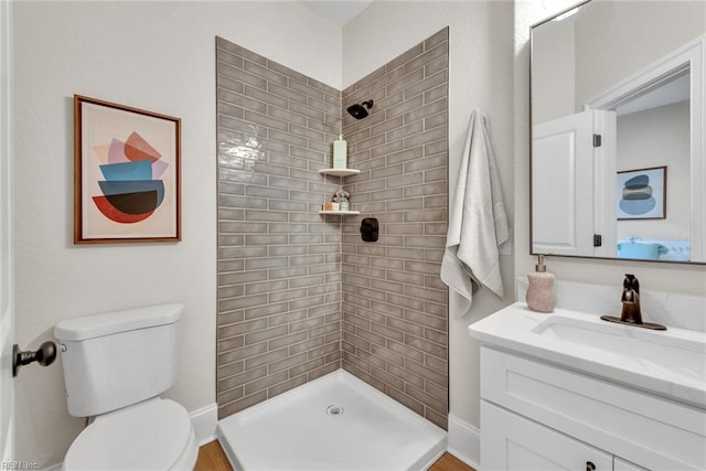 bathroom with vanity, toilet, and a tile shower