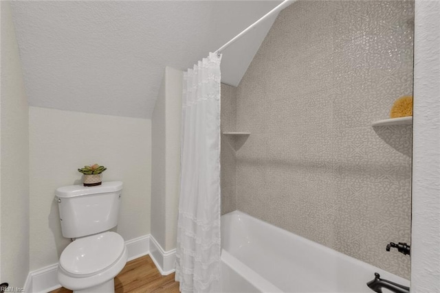 bathroom with hardwood / wood-style flooring, shower / bath combo, lofted ceiling, and toilet