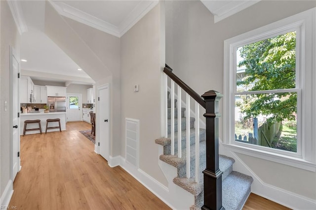 stairway with wood-type flooring and ornamental molding