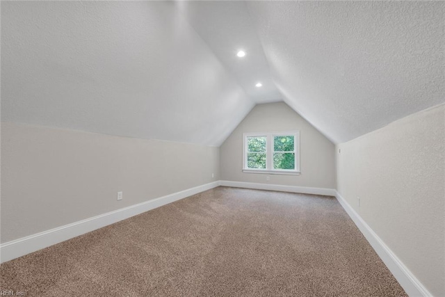 bonus room with lofted ceiling, a textured ceiling, and carpet