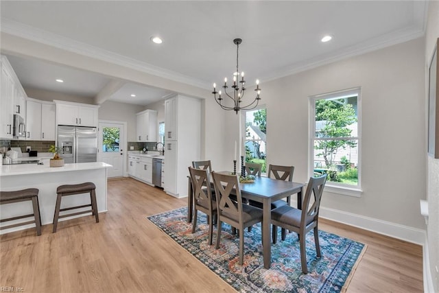 dining room featuring sink, crown molding, a chandelier, light hardwood / wood-style floors, and beamed ceiling